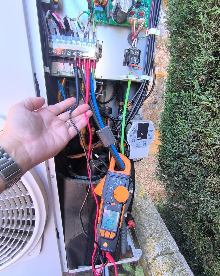 Técnico de Arisat midiendo con pinza amperimétrica en una unidad exterior